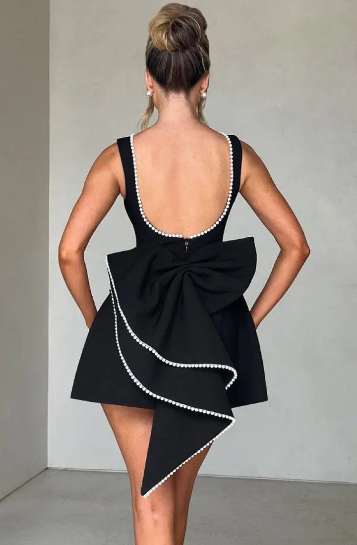 Back view of black cocktail dress showing pearl-trimmed bow and scoop back