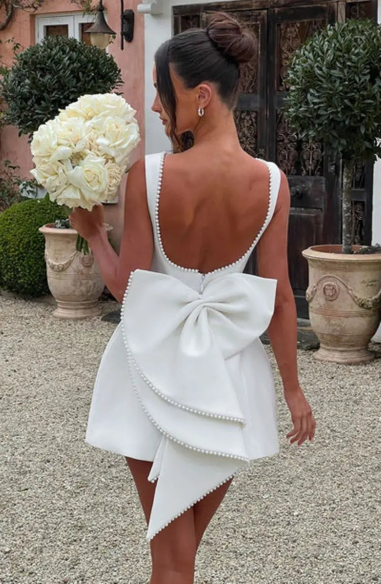 Ivory mini dress with oversized bow and pearl-edged low back