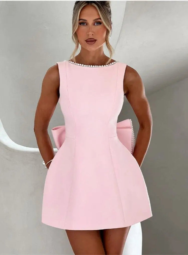 Pink sleeveless mini dress featuring pearl trim and side bow detail