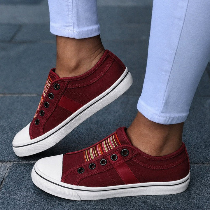 Burgundy canvas slip-on trainers featuring striped detail and white rubber sole