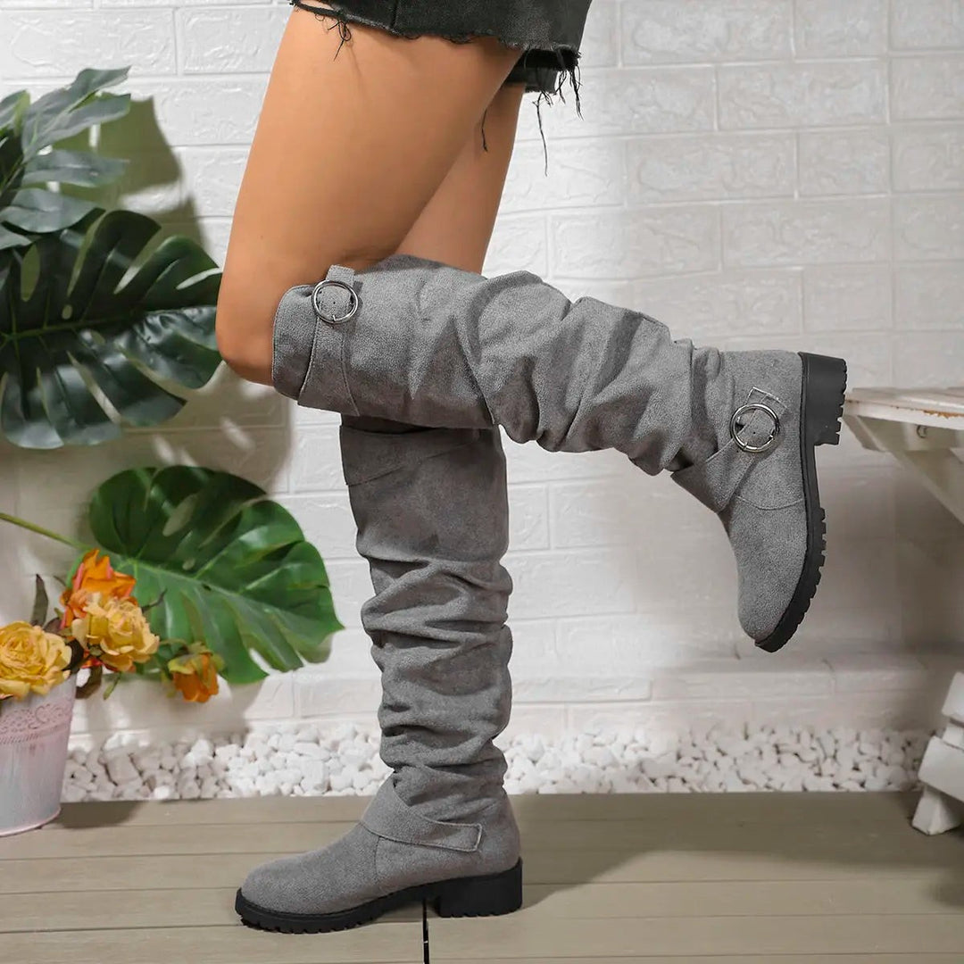 Grey suede knee-high boots featuring ruched shaft and silver buckle trim