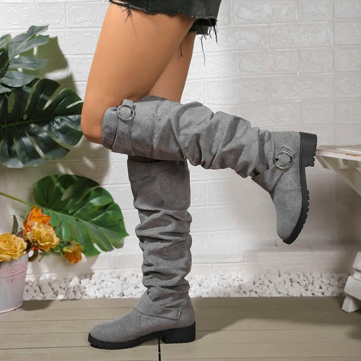 Grey suede knee-high boots featuring ruched shaft and silver buckle trim