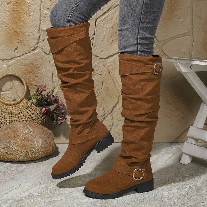 Tan suede knee-high boots showing ruched design and rounded buckle accent