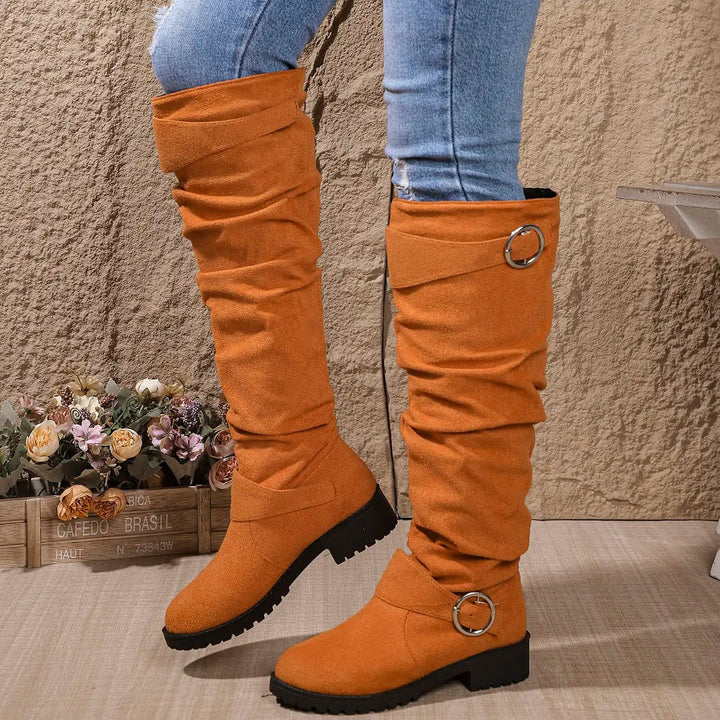 Burnt orange knee-high boots featuring ruched leg and buckle fastening