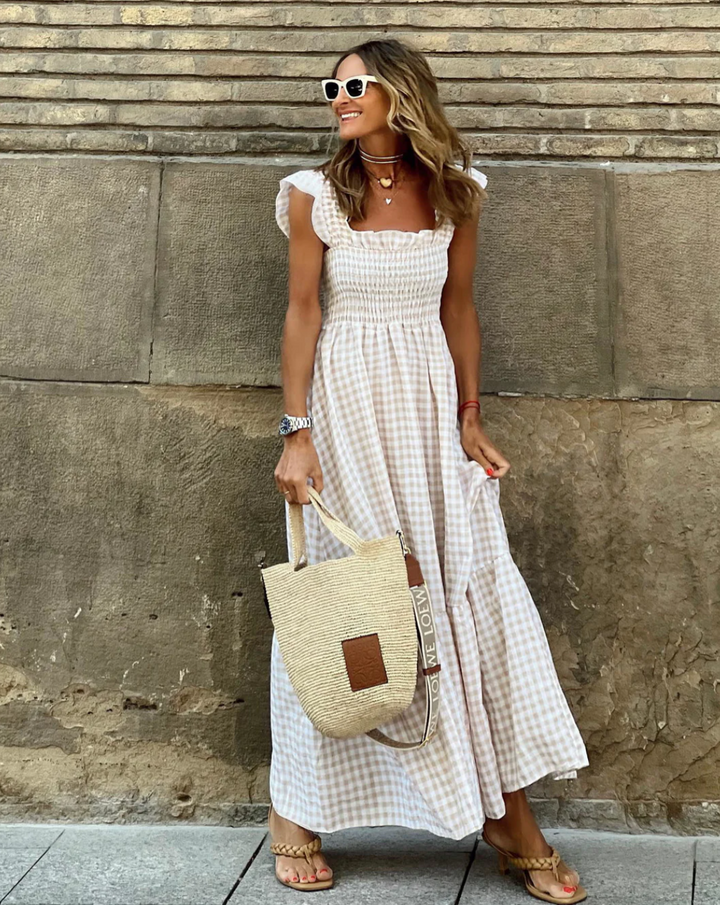 Beige gingham smocked maxi dress styled with woven tote and strappy heels