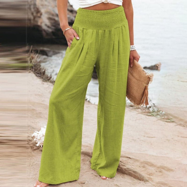 Lime green wide-leg trousers with smocked waistband, styled on beach sand