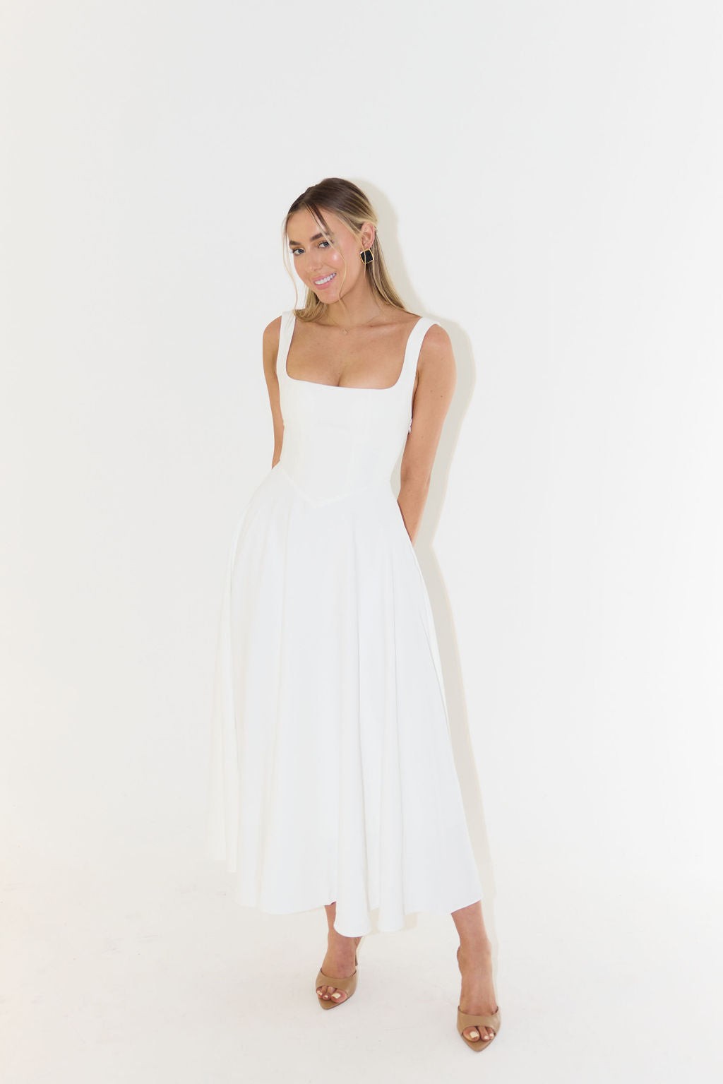Model wearing white sleeveless maxi dress with full circle skirt and nude heels