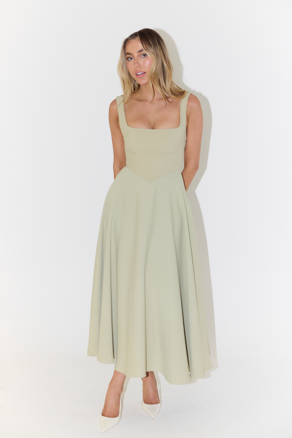 Sage green sleeveless A-line maxi dress with fitted bodice and pointed pumps