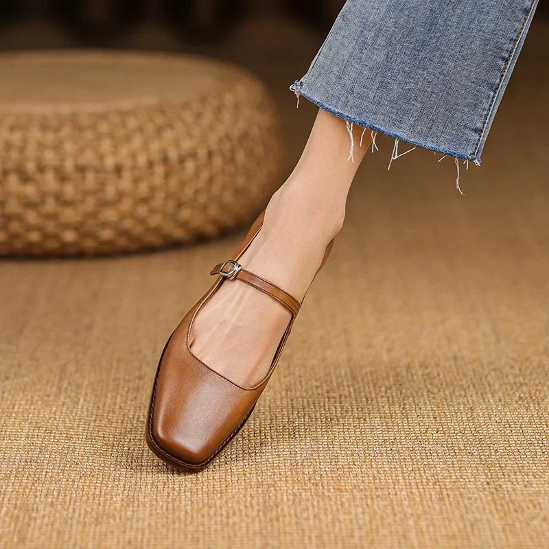 Model stepping in tan leather Mary Jane shoes with square toe and ankle strap