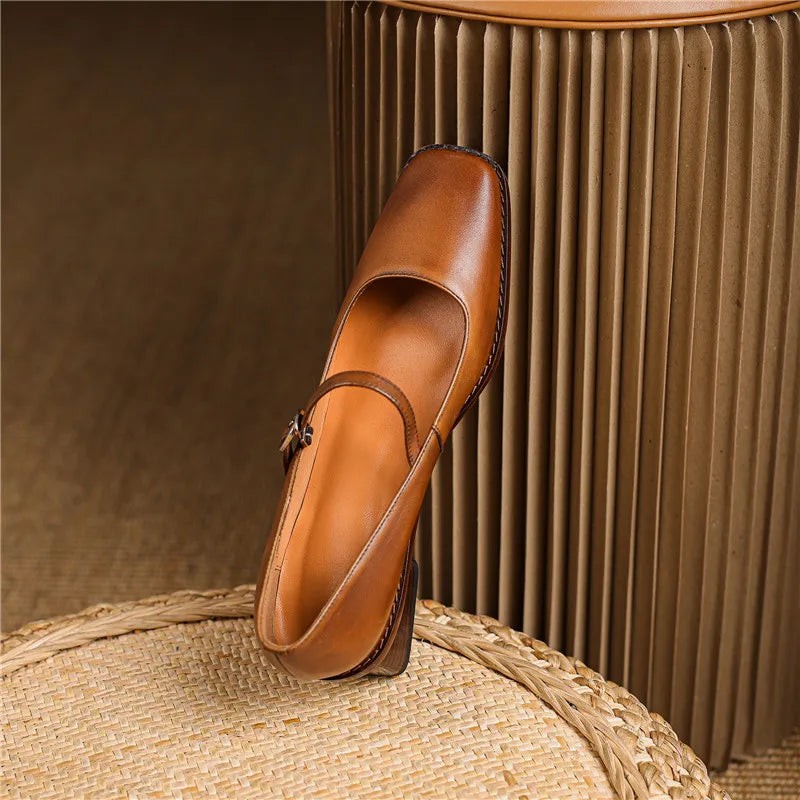 Tan leather block heel Mary Jane shoe balanced on woven rattan stool