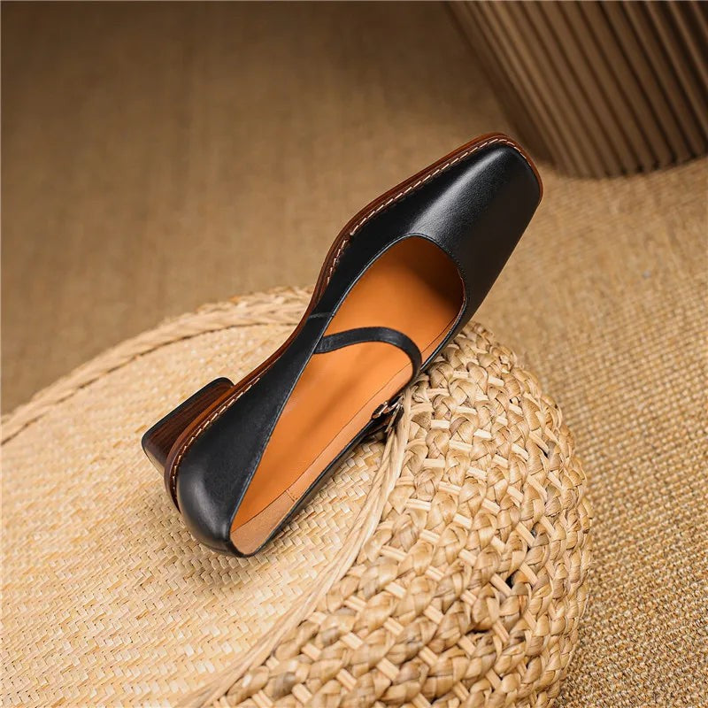 Black leather Mary Jane shoe resting on side, showing tan insole and block heel