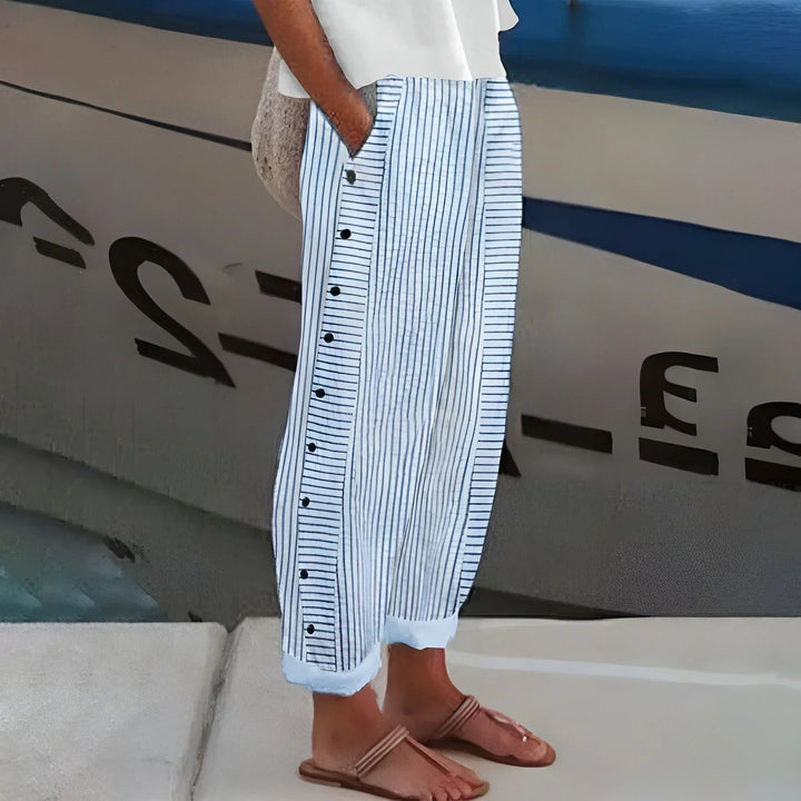 Blue and white striped wide-leg trousers with button side detail, styled poolside