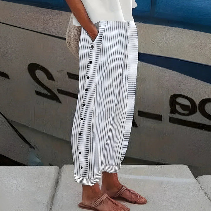 White striped trousers with contrast button trim, worn with tan flat sandals