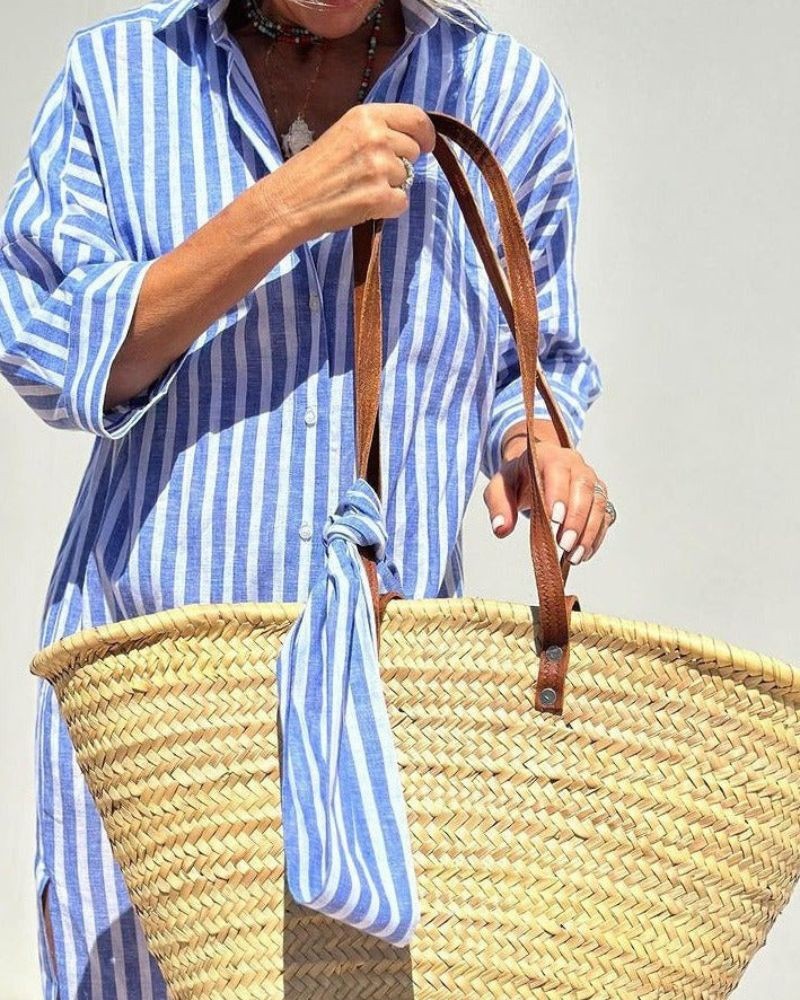 Close-up of blue striped shirt dress fabric tied to leather-handled straw tote