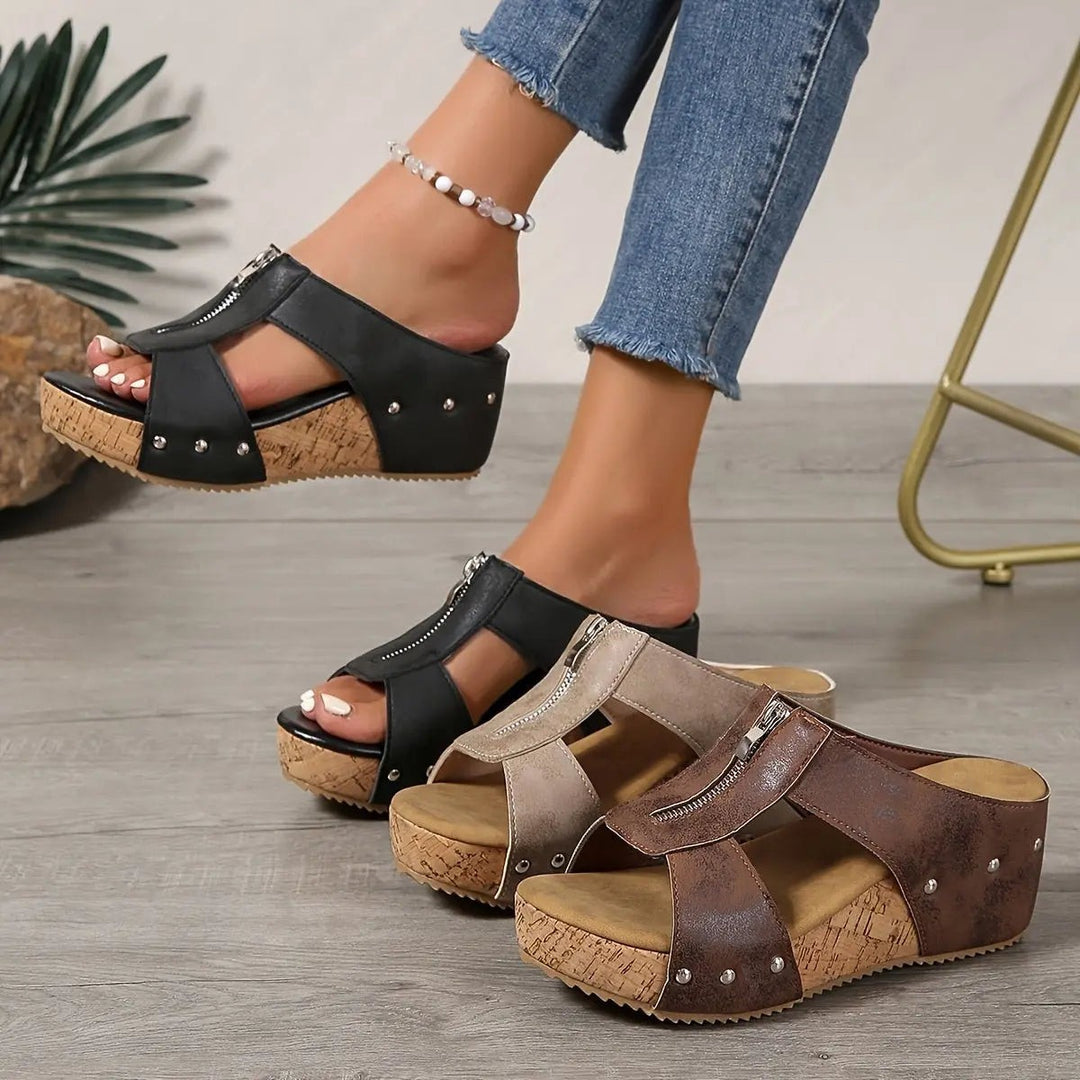 Black and brown open-toe cork wedge sandals with front zip detail, worn side by side
