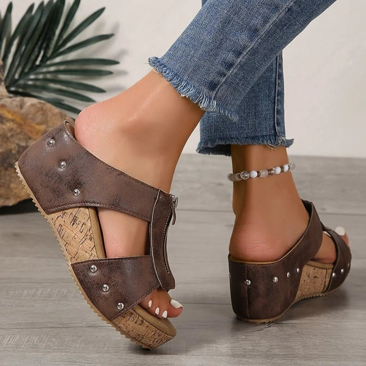 Black cork wedge sandals held side by side, revealing zip and cushioned sole