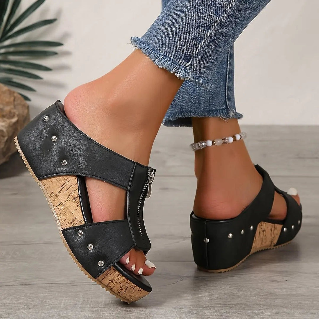Black cork wedge sandal viewed from behind, highlighting studded ankle strap