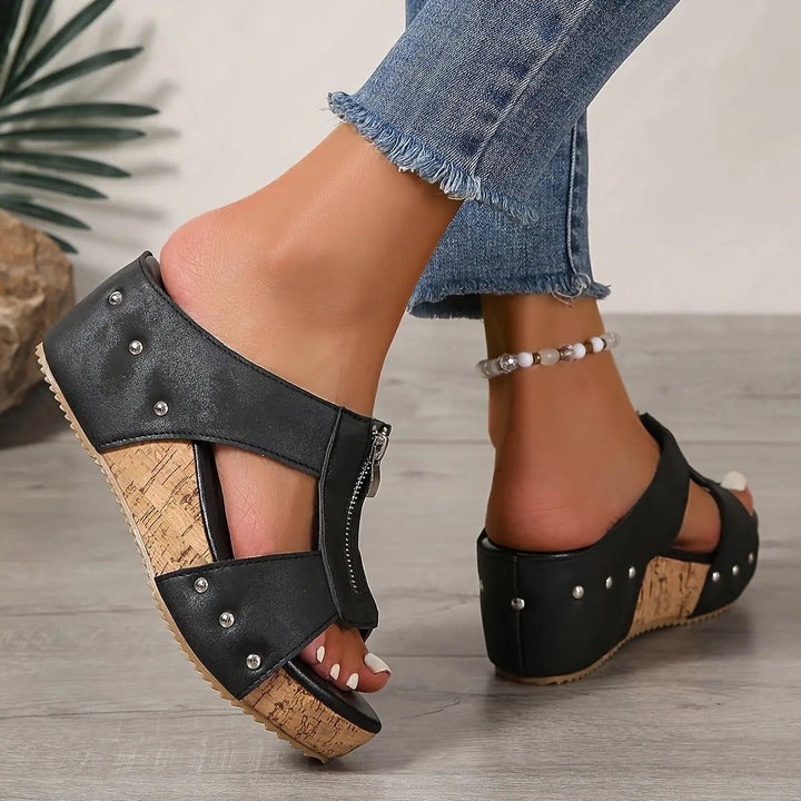 Black cork wedge sandal viewed from behind, highlighting studded ankle strap