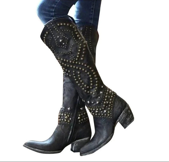 Black knee-high studded boots worn with jeans, pointed toe and block heel