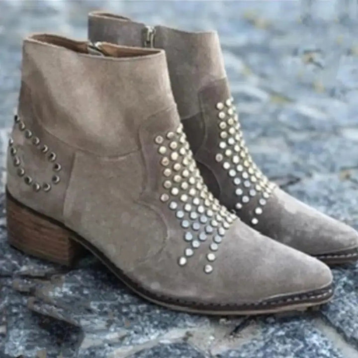 Pair of taupe suede ankle boots with stud detailing on stone flooring