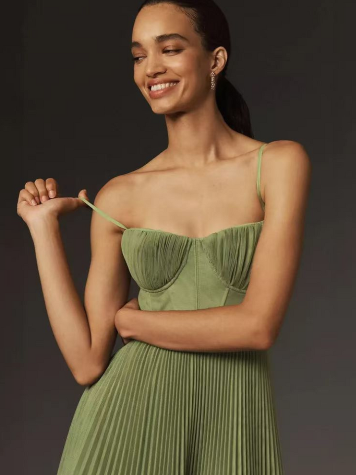 Smiling model adjusting strap of sage green pleated bustier maxi dress