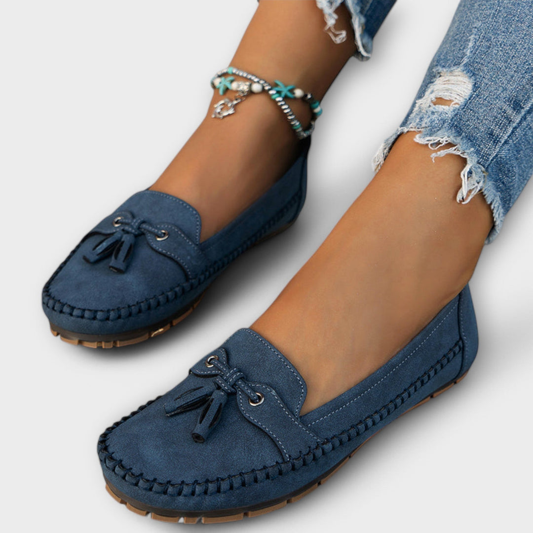 Navy suede tassel loafers worn with ripped jeans, showing stitched moccasin detailing
