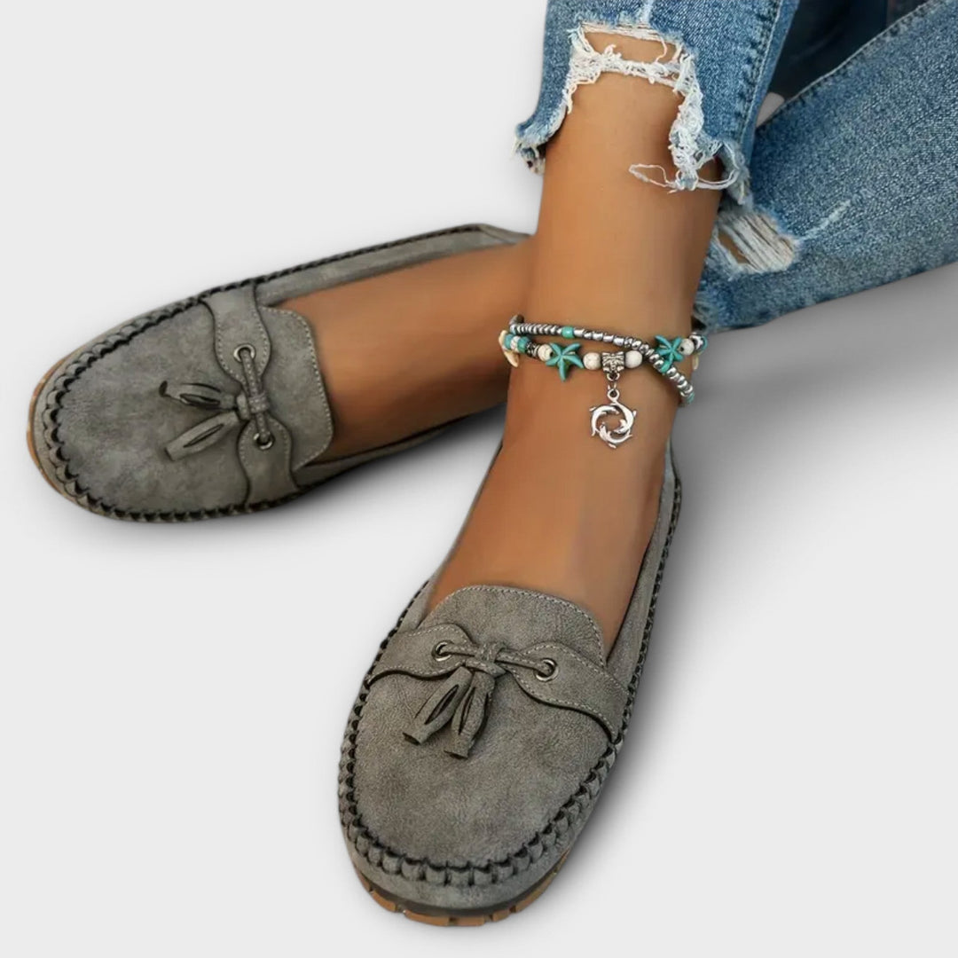 Grey suede tassel loafers with whipstitch trim, paired with a boho anklet