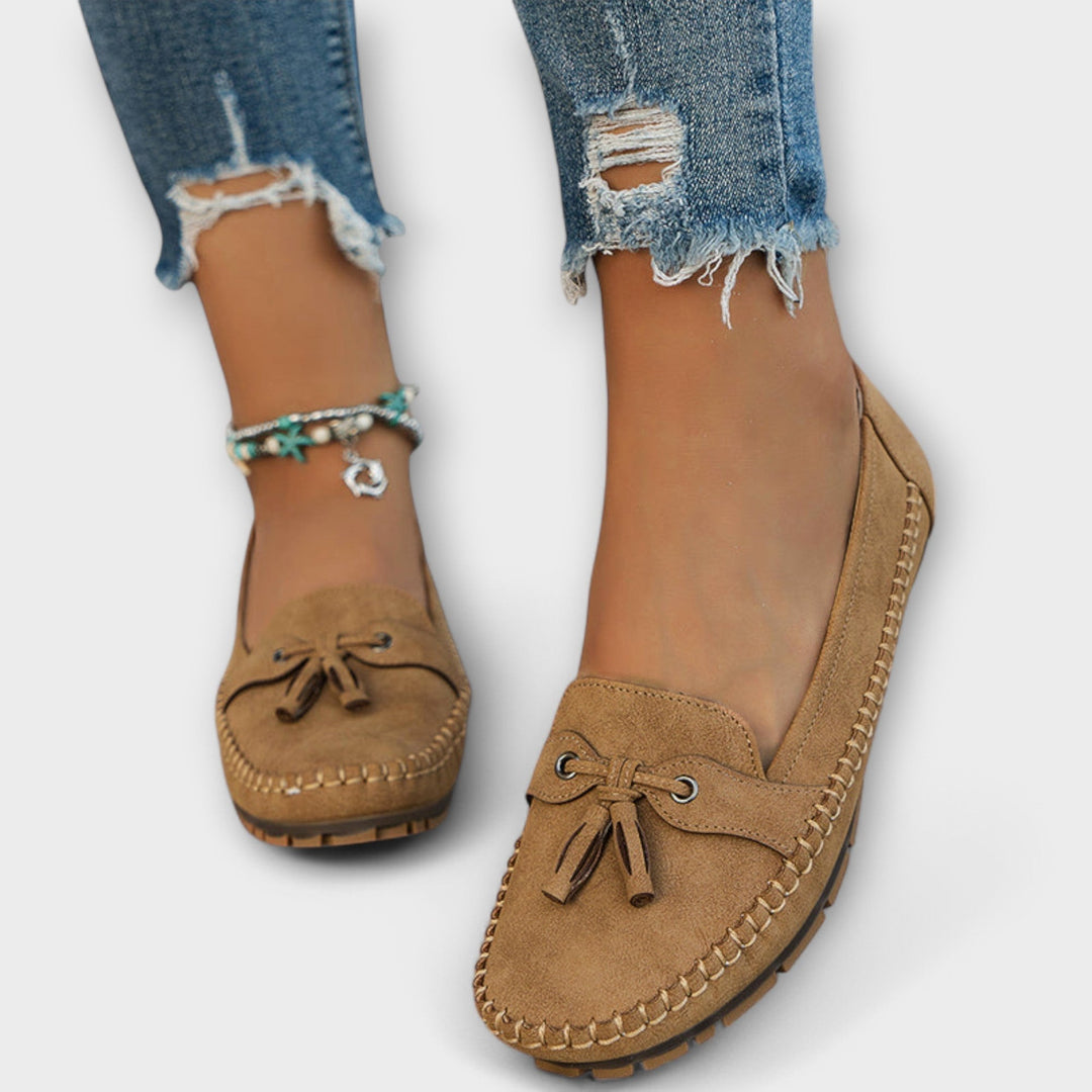 Tan suede tassel loafers with contrast stitching, worn barefoot with ripped denim