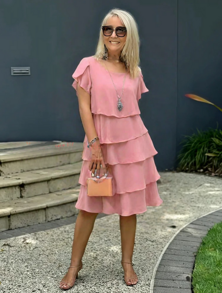 Dusky pink tiered midi dress with flutter sleeves and gold necklace