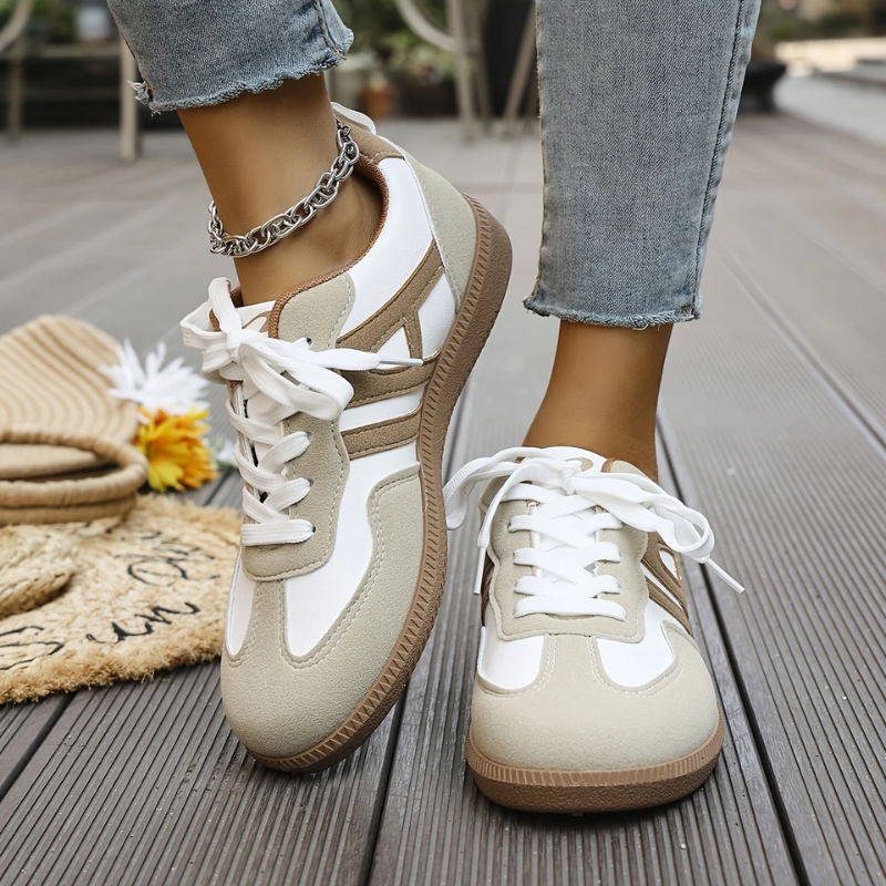 Beige and white lace-up trainers worn with cropped jeans on decking