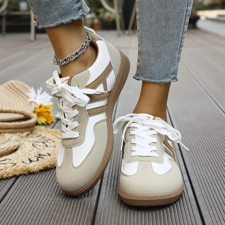 Beige and white lace-up trainers worn with cropped jeans on decking