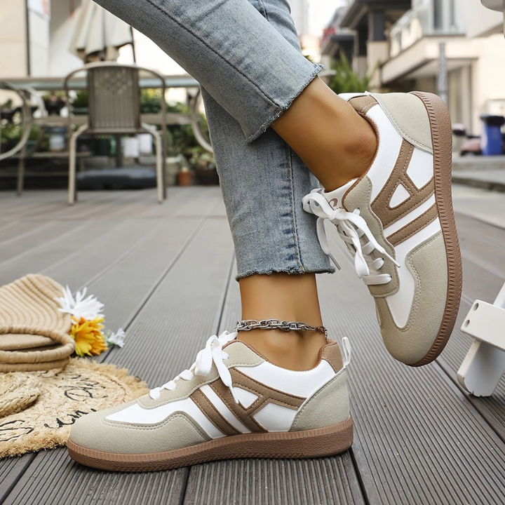 Two-tone trainers with contrast stripes shown mid-step outdoors
