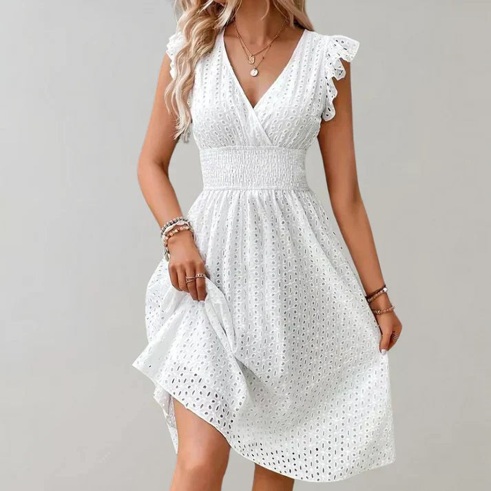 Close-up of white cotton midi dress showing smocked waistband and eyelet lace detailing
