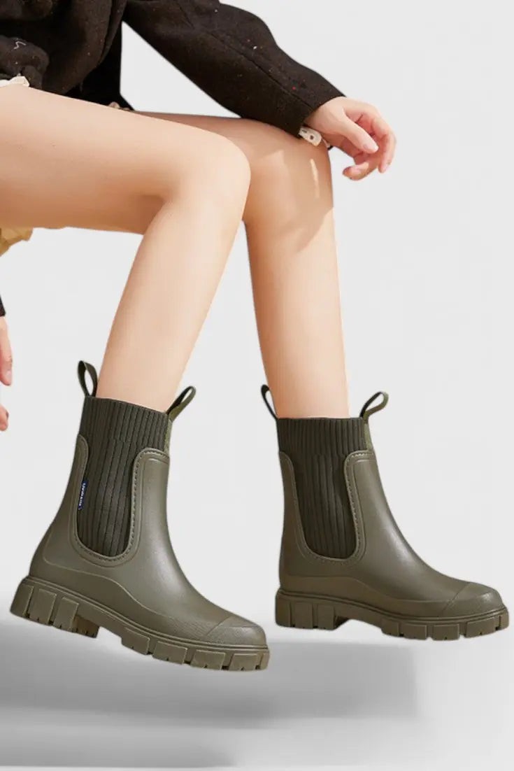Khaki green Chelsea rain boots worn on model, seated close-up view