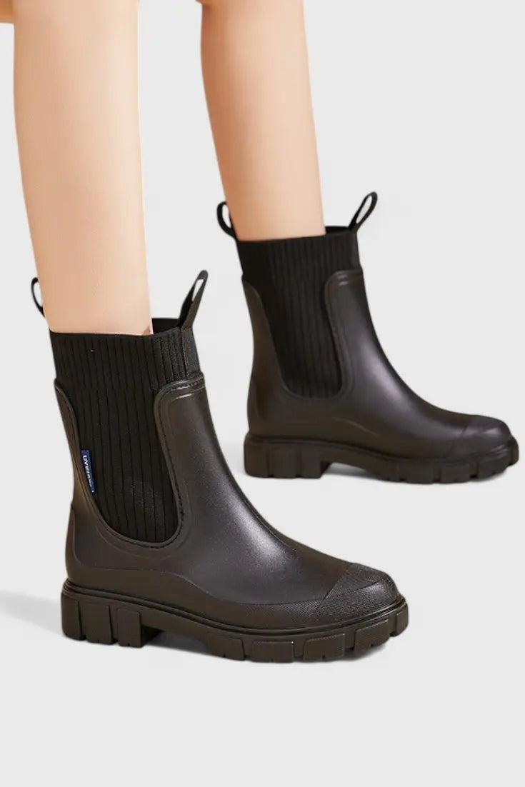 Black waterproof Chelsea boots worn on model, close-up side view