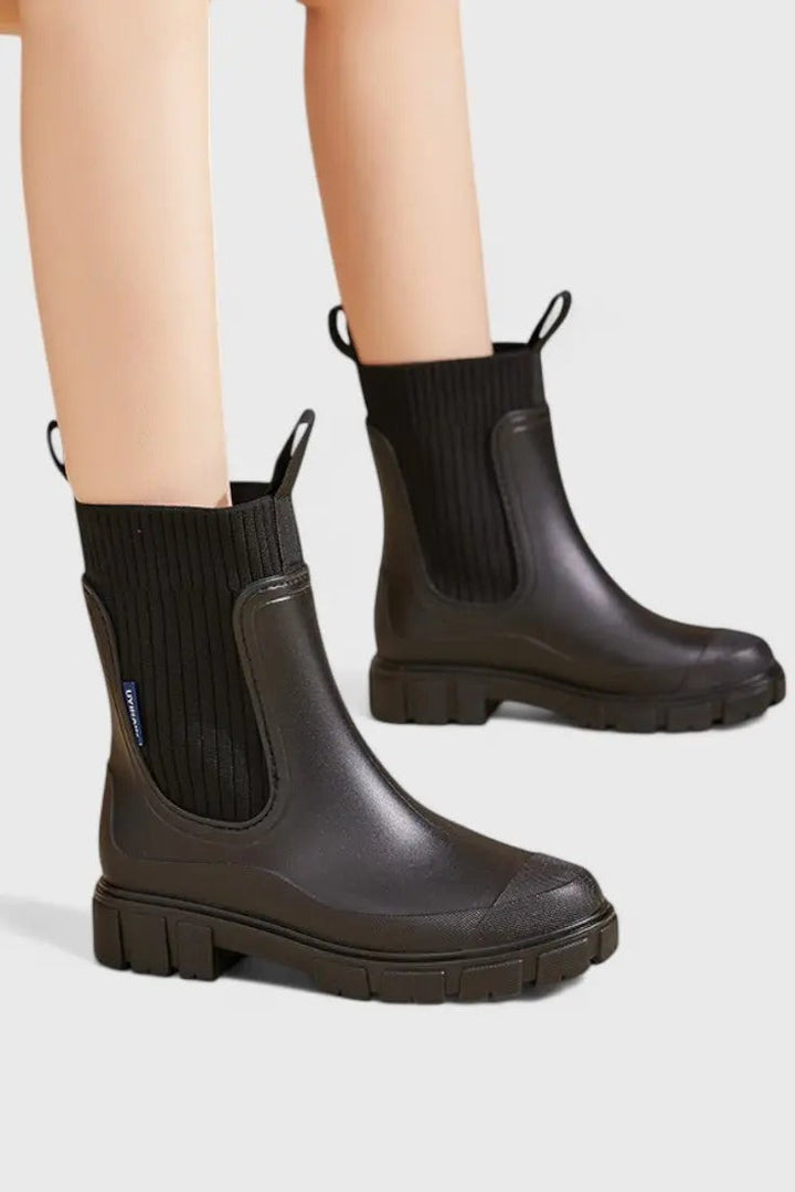 Black waterproof Chelsea boots worn on model, close-up side view