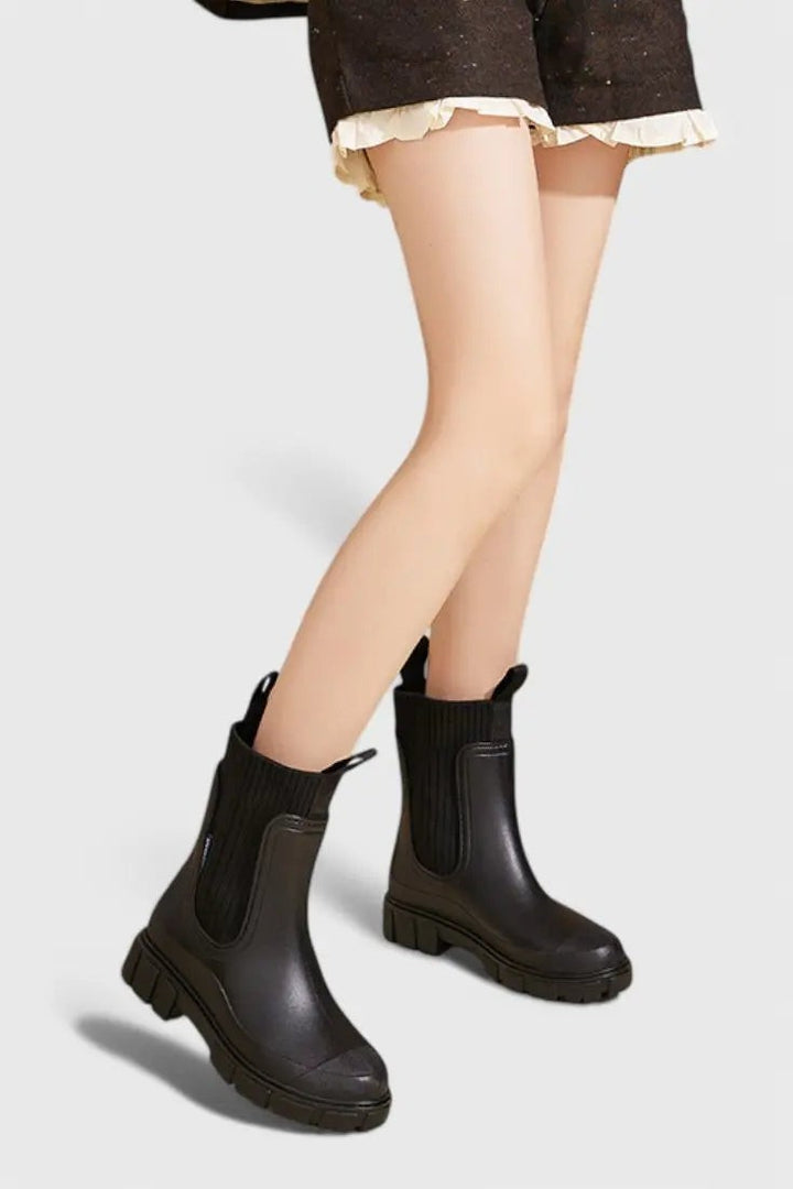 Black waterproof Chelsea boots worn on model with pull-tab detail