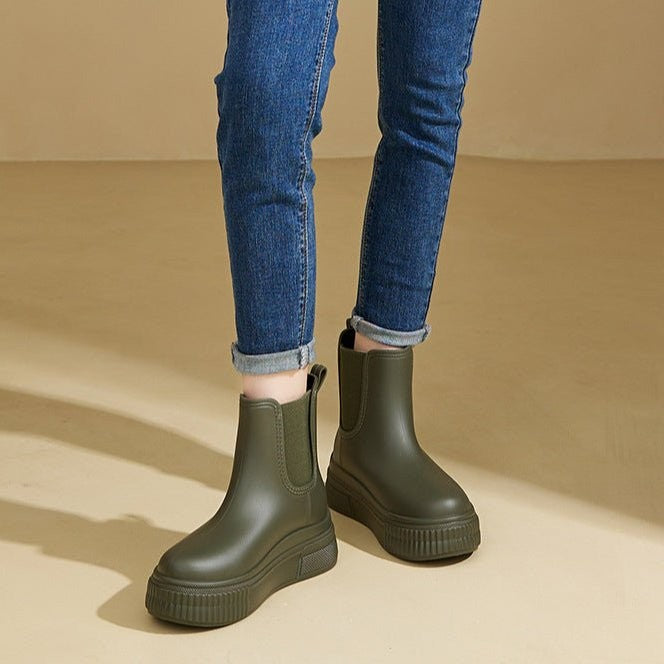Model wearing khaki green Chelsea rain boots with cuffed denim jeans