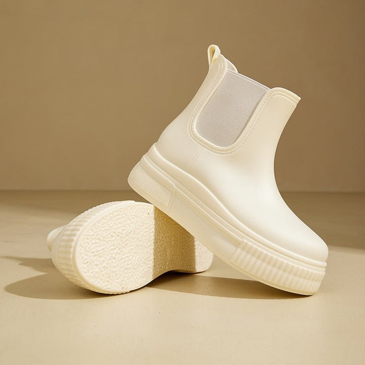 Cream Chelsea rain boots displayed with soles facing upwards on floor