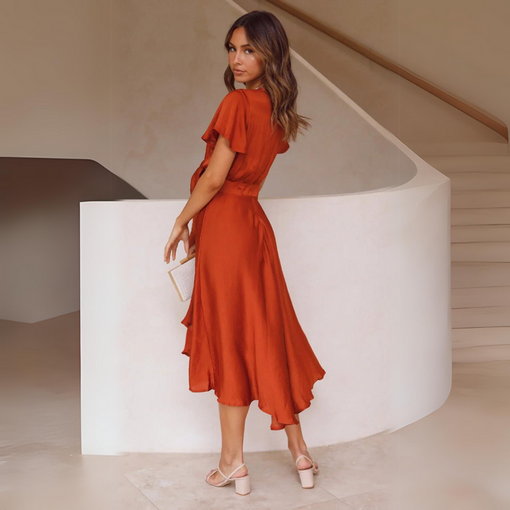 Rear view of burnt orange midi dress showing flutter sleeves and cut-out waist